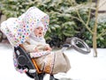 Sad crying little baby girl sitting in the pram or stroller on winter day. Unhappy upset tired and exhausted child in Royalty Free Stock Photo