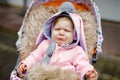 Sad crying little beautiful baby girl sitting in the pram or stroller on autumn day. Unhappy tired and exhausted child Royalty Free Stock Photo