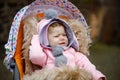 Sad crying little beautiful baby girl sitting in the pram or stroller on autumn day. Unhappy tired and exhausted child Royalty Free Stock Photo