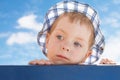 Sad cute little boy in hat on sky background Royalty Free Stock Photo