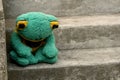Sad depressed abandoned green frog plush toy plushie sitting on the stairs alone, feeling down, sadness, depression, alienation,