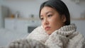 Sad depressed Asian woman in home kitchen alone wrapped warm blanket thinking deep thoughts problem depression pensive Royalty Free Stock Photo