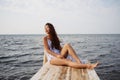 Sad depressed asian woman sitting alone lonely on wooden bridge looking at outdoor ocean. Royalty Free Stock Photo