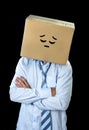 Sad and depressed businessman wearing cartoon smiley face painted on cardboard box over his head Royalty Free Stock Photo
