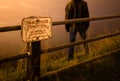 Sad/depressed man standing on top of a cliff behind a danger sign