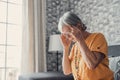 Sad depressed middle aged mature woman sitting alone at home touching head feeling headache migraine, upset tired old senior lady Royalty Free Stock Photo