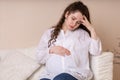 Sad, depressed pregnant woman suffering from headache, migraine, feeling sick, holding hand on head, Royalty Free Stock Photo