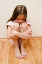 Sad and depressed punished little girl child sitting on the floor near the wall Royalty Free Stock Photo