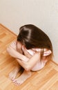 Sad and depressed punished little girl child sitting on the floor near the wall Royalty Free Stock Photo