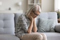 Sad depressed retired blonde woman sitting on sofa at home Royalty Free Stock Photo