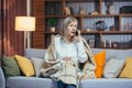 Sad depressed senior woman at home talking on the phone sitting on the couch in the evening Royalty Free Stock Photo