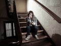 Sad depressed unhappy teenager girl suffering from cyberbullying by mobile smart phone sitting alone Royalty Free Stock Photo