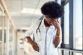 Sad and depressed young african american female doctor in white uniform standing in corridor Royalty Free Stock Photo