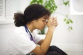 Sad depressed young african american nurse sitting on floor with frustrated face expression Royalty Free Stock Photo