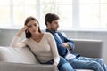 Sad depressed young caucasian wife ignores unhappy husband sitting on sofa in living room interior Royalty Free Stock Photo