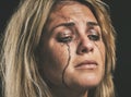 Sad, depression and woman crying with makeup smudge on face from tears with studio wall closeup. Depressed, hopeless and Royalty Free Stock Photo