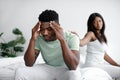 Sad despaired millennial african american woman calms depressed man at bed in bedroom interior