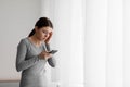 Sad despaired young european lady receiving bad news on smartphone at home interior