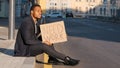 Sad desperate frustrated ethnic employee office worker African American man male guy sitting on steps outdoors holding Royalty Free Stock Photo