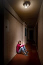 Sad and desperate woman sits in a dark corridor