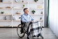 Sad disabled senior man sitting on wheelchair alone at retirement home, looking through window Royalty Free Stock Photo