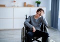 Sad disabled teenager sitting in wheelchair alone at home, copy space. Depression in handicapped teens Royalty Free Stock Photo