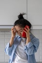 Sad disappointed Asian girl listening bad news over phone while standing in kitchen at home Royalty Free Stock Photo