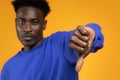 Sad disappointed young black man showing thumb down, yellow background Royalty Free Stock Photo