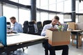 Sad dismissed worker are taking his office supplies with him from office