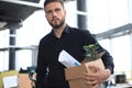 Sad dismissed worker is taking his office supplies with him from office