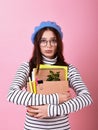 Young lady student in a stylish beret hat, with a cardboard box in her hands on a pink background Royalty Free Stock Photo