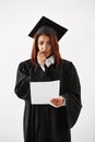 Sad displeased african female graduate looking at camera holding test over white background. Royalty Free Stock Photo