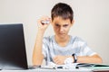 Sad dissapointed kid doing homework on laptop computer. Boy hand squeezing a crumpled ball of paper. School, remote Royalty Free Stock Photo