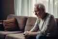 Sad elderly man depressed, feeling lost, lonely at home. Mental Alzheimer disease, memory loss, sitting on sofa at home