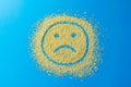 Sad emoji smile on a blue background. Smiley from yellow sugar grains. Stock image.