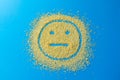 Sad emoji smile on a blue background. Smiley from yellow sugar grains.