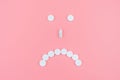 Sad emoticon from medical pills on a blue background. Health support. Treating depression with antidepressants