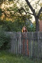 A sad expectant girl stands behind a wooden palisade in a village attire Royalty Free Stock Photo