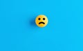 Sad face emoticon or icon on a ball on blue background. Negative feedback Royalty Free Stock Photo