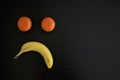 Sad face made out of fruits on black background