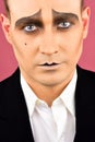 Sad face. Mime artist. Comedian or tragedian performer. Mime with face paint. Man with mime makeup. Theatre actor miming