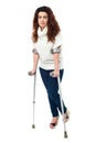 Sad faced woman limping with crutches