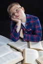 A sad fat boy with glasses sits with books at the table. Black background. Education and knowledge. Close-up. Vertical Royalty Free Stock Photo