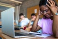 Sad female black teen high school student being bullied by classmates in class. Focus on foreground. Bullying. Royalty Free Stock Photo