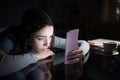 Sad female checking phone content in the night at home Royalty Free Stock Photo