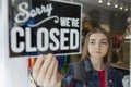 Sad Female Owner Of Small Business Turning Round Closed Sign In Shop Window Royalty Free Stock Photo