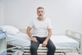 Sad female patient seated alone on hospital bed staring ahead