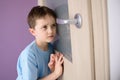 Sad, frightened child listening to a parent talking through the door