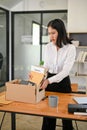 A sad and frustrated Asian female office worker packing her stuff, being fired from her boss Royalty Free Stock Photo