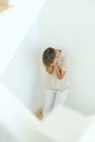 Sad frustrated teenage boy hides his face standing on staircase alone. Education difficulties, problem with family